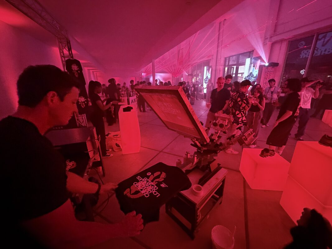 Merch Troop operator pressing a full-color custom transfer onto a shirt at a live event station