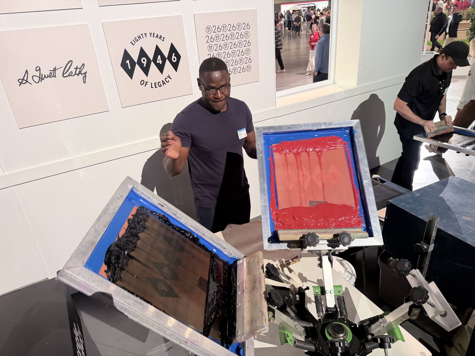 Attendees examining screenprinted and decorated products at an active event booth with display tables